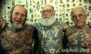 Фотография трех пожилых мужчин с обширными татуировками на теле, демонстрирующими многолетний опыт и любовь к искусству татуировки.