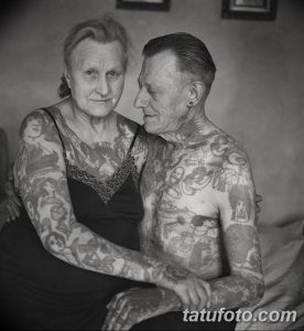 Фотография пожилой пары, у которых на руках и теле множество татуировок, демонстрирующих их долгую и насыщенную жизнь.