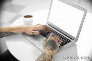 Фото тату: руки мужчины с татуировками, работающего за ноутбуком. Видны татуировки на пальцах, кистях и предплечьях.