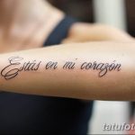 Фото тату надписи на испанском языке на руке. Фраза 'Estás en mi corazón' выполнена красивым каллиграфическим шрифтом черными чернилами.