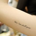 Фото тату надписи на руке. Текст 'this too shall pass' выполнен простым шрифтом черными чернилами. Минималистичный дизайн.