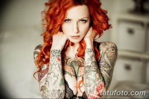 Фотография рыжеволосой девушки с множеством татуировок на руках и груди. Рисунки включают цветы, бабочек и геометрические узоры.