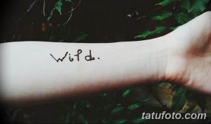Фото татуировки с надписью "Wild." на запястье. Рисунок выполнен черными чернилами простым рукописным шрифтом.