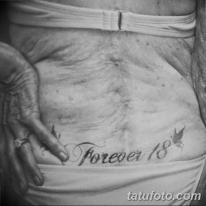 Фото татуировки на животе с надписью "Forever 18" и изображением бабочки, выполненной в черно-белых тонах.