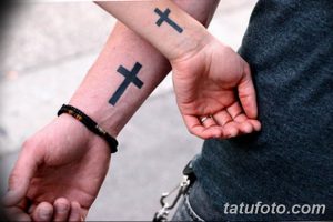 Фото минималистичных татуировок в виде крестов на запястьях двух людей, демонстрирующих простоту и религиозную символику.