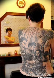 Фото тату: большая татуировка на спине, изображающая портреты людей и пейзаж с деревьями и цветами.