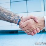 Фото рукопожатия, на котором видно татуированное предплечье с изображением дракона. Черно-серые тона.
