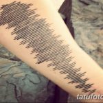 Фотография татуировки на руке, изображающей звуковую волну. Черные линии создают абстрактный и динамичный рисунок.