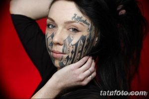 Фото тату на лице женщины: сложный узор, покрывающий большую часть лица, и надпись 'All for love'. Яркий пример боди-арта и самовыражения.