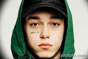 Фото молодого человека с татуировкой "wake up" под глазом. Простой, но выразительный дизайн.