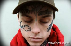 Фото татуировок на лице молодого человека. Изображены абстрактные узоры, символы и линии в черном и синем цветах.