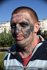 Фото татуировок на лице мужчины. Изображены портреты, надписи и узоры в черном цвете. Экстремальный и вызывающий стиль.