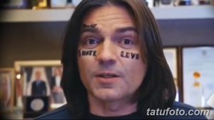 Фото тату с надписями 'Hate' и 'Love' под глазами мужчины. Татуировки выполнены черными чернилами, выглядят контрастно и провокационно.