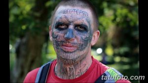 Фото тату: экстремальная татуировка на лице мужчины, изображающая жуткий грим с черепом и надписями. Мрачный и пугающий дизайн.
