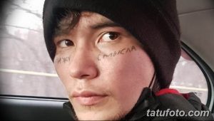 Фото молодого человека с татуировками на лице, включая надписи 'Смысла' и 'Пижу'. Вызывающий и неоднозначный рисунок, выполненный черными чернилами.