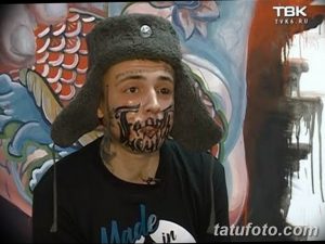 Фотография мужчины с яркой татуировкой в виде маски на лице. Демонстрация смелого и артистичного стиля татуировки.