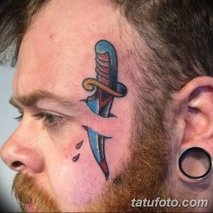 Фотография мужчины с татуировкой кинжала на щеке. Кинжал выполнен в традиционном стиле с использованием ярких цветов.