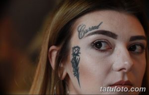 Фото тату: надпись "Cursed" на лбу и татуировка бриллианта под глазом девушки. Необычный и провокационный эскиз тату.