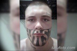 Фото тату: крупная надпись "NAS" на лице мужчины, выполненная черными чернилами. Необычный и вызывающий эскиз тату.