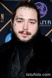 Фото тату: Post Malone с многочисленными татуировками на лице, включая надпись 'Stay Away', колючую проволоку и другие символы. Узнаваемый стиль и яркий образ.