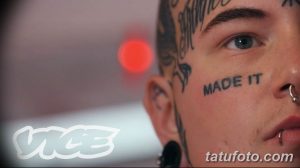 Фото тату: надпись 'MADE IT' черными чернилами на щеке мужчины. Минималистичный дизайн, акцент на тексте и выразительный взгляд.