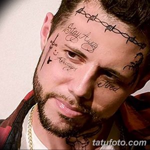 Фото тату: мужчина с татуировками на лице, включая надписи 'Stay Away', 'Love is Always', 'Fired' и изображение колючей проволоки.