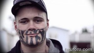Фото тату на лице мужчины. Изображена татуировка в виде улыбки, покрывающей нижнюю часть лица. Черно-белая графика, минимализм.