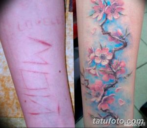 Фото татуировки с изображением цветущей ветки сакуры, выполненной в технике акварели, скрывающей шрамы на руке. Нежный и романтичный рисунок тату.