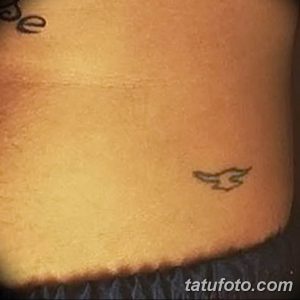 Фото минималистичной татуировки с изображением летящей птицы. Простой и элегантный дизайн в черно-серых тонах.