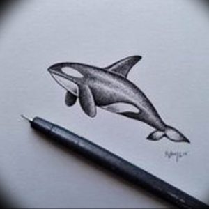 Эскиз татуировки косатки, выполненный карандашом. Изображение отличается высокой детализацией и реалистичностью. Рядом с рисунком лежит карандаш.