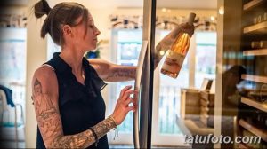 Фото тату: татуировка с изображением буддийского символа и цветочных элементов на руке женщины.