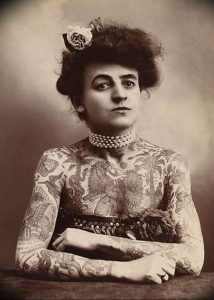 Фотография женщины с обширными татуировками в стиле начала 20 века. Историческое изображение, демонстрирующее ранние формы татуировки.