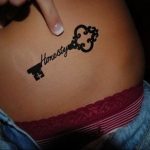 Фото минималистичной татуировки ключа с надписью 'Honesty' на боку девушки. Идеально для поиска идей для небольших и символичных татуировок.