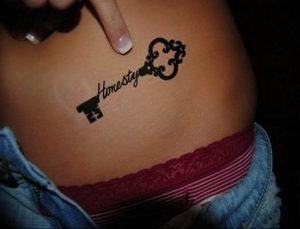 Фото минималистичной татуировки ключа с надписью 'Honesty' на боку девушки. Идеально для поиска идей для небольших и символичных татуировок.