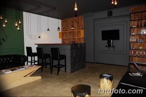 Фото тату-салона, оформленного в стиле бара: барная стойка, стулья, освещение и декор. Оригинальный и необычный дизайн.