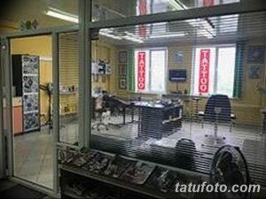 Фото фасада тату-салона с яркой вывеской 'TATTOO', большими окнами и витринами с эскизами. Современный дизайн и привлекательный внешний вид.