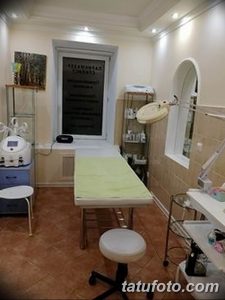 Фото рабочего места мастера тату: кушетка, инструменты, стерилизатор и освещение. Интерьер в светлых тонах, акцент на гигиене.