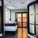 Фото ресепшена тату-студии с белой стойкой, компьютером и удобным креслом для администратора. Светлый и современный интерьер.
