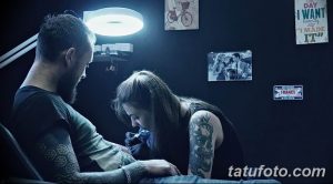 Фото процесса нанесения татуировки: мастер сосредоточенно работает над рисунком на руке клиента. В студии приглушенный свет и уютная атмосфера.