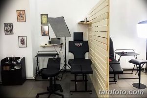 Фото интерьера тату-студии с удобными креслами, рабочими местами и стерильным оборудованием. Стены украшены эскизами татуировок.