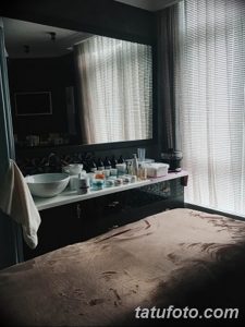 Фото зоны отдыха в тату-студии с белой столешницей, раковиной и занавесками. Атмосфера спокойствия и уюта.