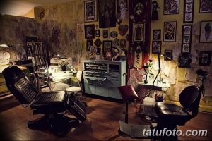 Фото интерьера тату-салона в темных тонах с религиозными изображениями на стенах, создающее атмосферу мистики и таинственности.