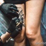 Фото тату процесса нанесения рисунка на ногу. Мастер в черных перчатках работает машинкой. Крупный план.