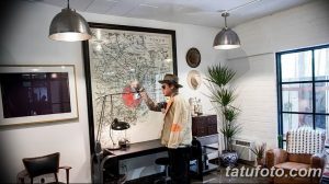 Фото креативной тату-студии с большой картой Токио на стене, стильным интерьером и мастером тату, работающим над эскизом. Атмосфера творчества и вдохновения.