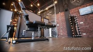 Фото тату-студии с современным черным креслом для татуировок, кирпичной стеной и стильным освещением. Интерьер для вдохновения и выбора мастера.