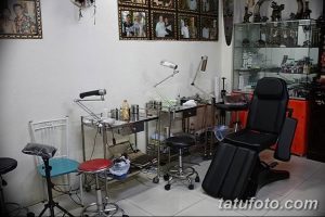 Фото уютной тату-студии с удобным креслом для клиента, стерильным оборудованием и портретами на стене.