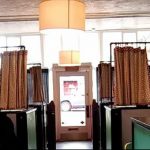 Фото минималистичной тату-студии с занавесками, разделяющими рабочие места, и приглушенным освещением. Интерьер выполнен в нейтральных тонах.