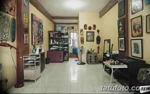 Фото тату-студии с бежевыми стенами, деревянной мебелью и множеством рисунков на стенах, создающей уютную атмосферу.