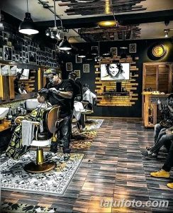 Фото тату-студии и барбершопа с темным интерьером, кожаной мебелью и портретами на стенах.