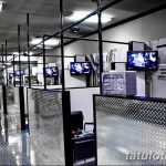 Фото современного тату-салона с металлическими перегородками, телевизорами и минималистичным дизайном. Профессиональное оборудование и чистота.